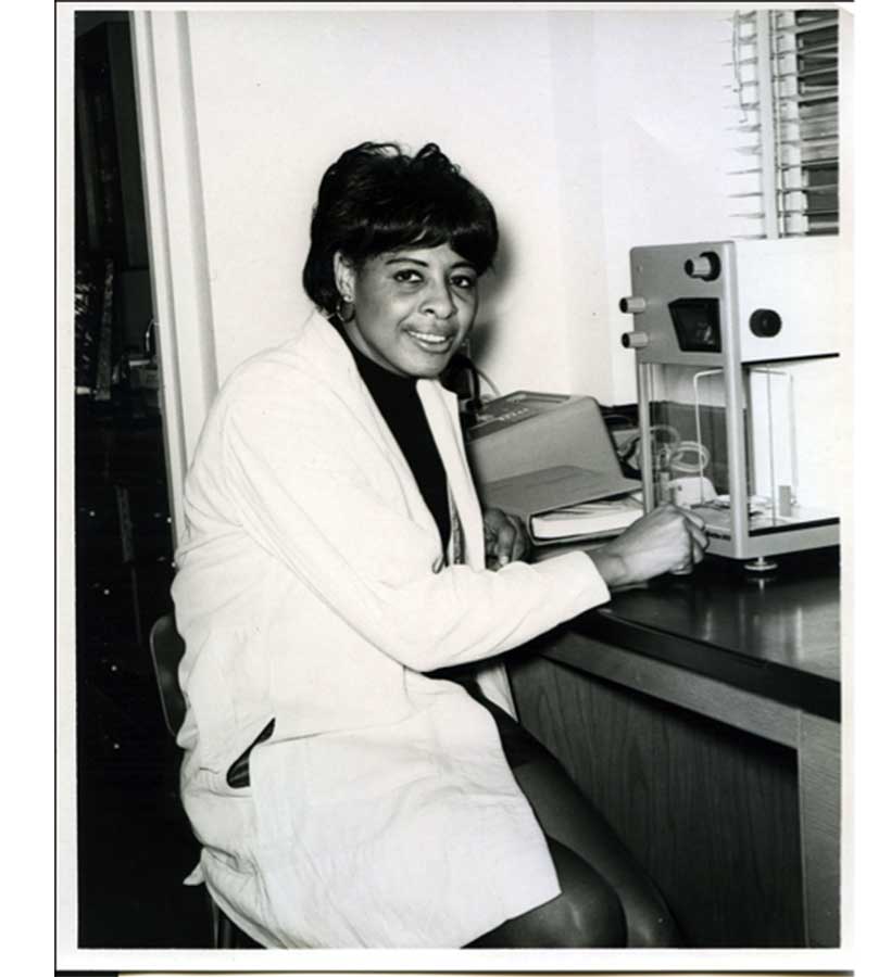 Dr. Rebecca Twine, Nancy's mother, sitting in front of lab equipment and smiling at the camera