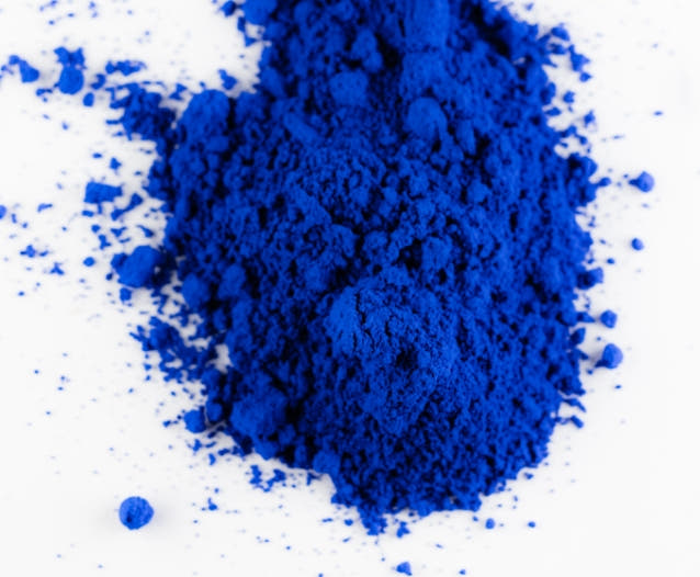 Bright blue copper peptide powder on white background. 