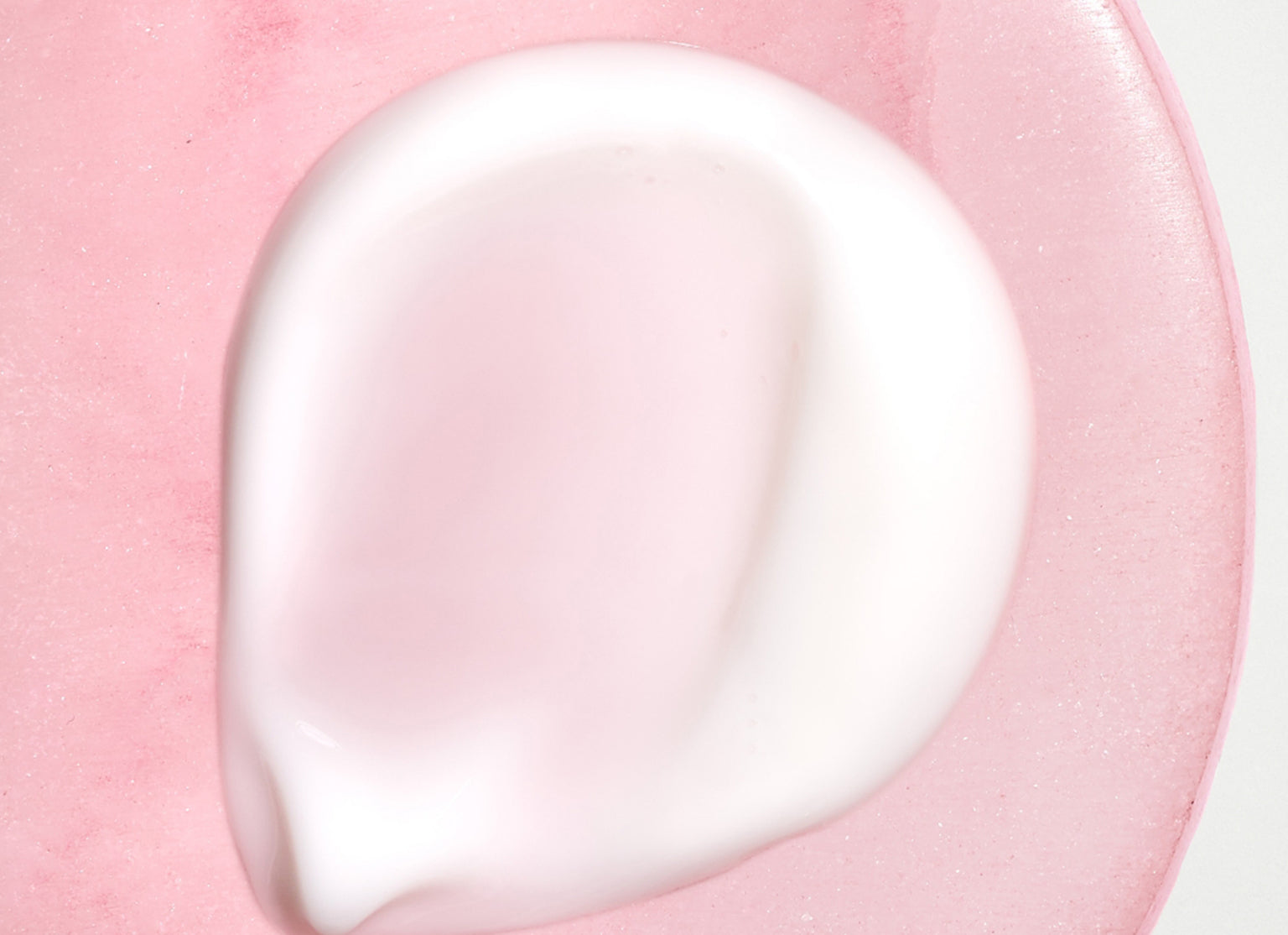 Swatch of Heat protectant creme on a pink background. 