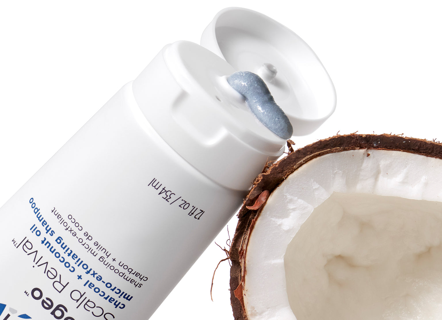 Scalp Revival Micro-Exfoliating Shampoo Tube resting on an open coconut. 