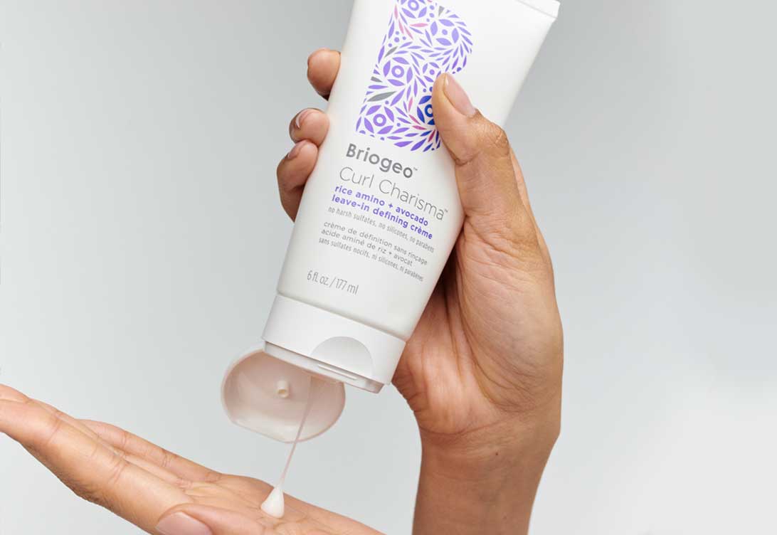Hand squeezing Curl Charisma rice amino leave-in defining creme into another hand