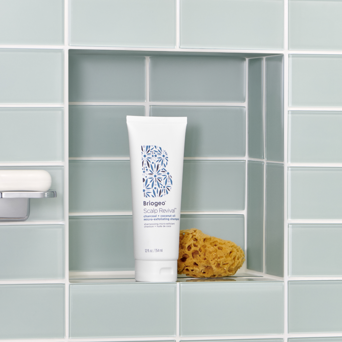 Scalp Revival Micro -Efoliating shampoo tube on a shower shelf next to a sponge and a bar of soap. 